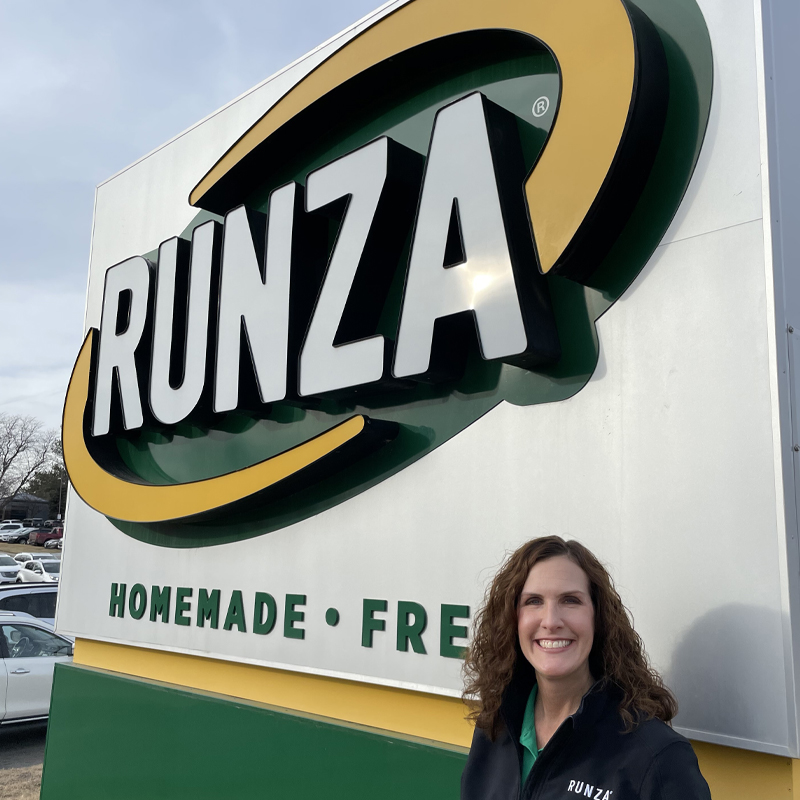40 Faces of 40 Years Becky Perrett, Director of Marketing at Runza, standing in front of a Runza sign
