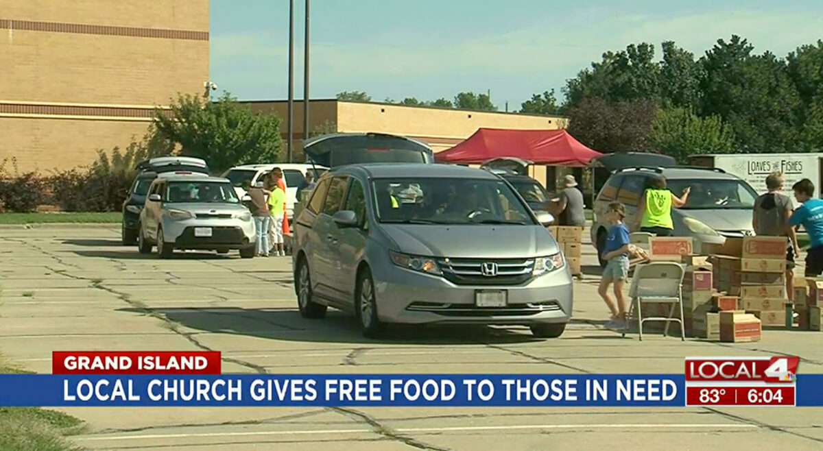 Photo of KSNB Local 4's coverage of Loaves and Fishes mobile pantry in Grand Island, Nebraska vehicles in line to receive food and volunteers working to load vehicles