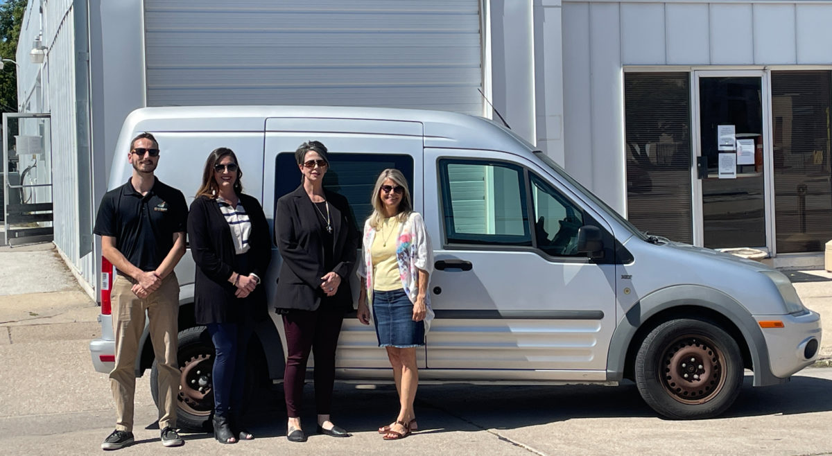 Photo of Jake Kampschneider, Food Bank for the Heartland Community Support Representative, and Care Corps' LifeHouse team members with the transit van donated by the Food Bank