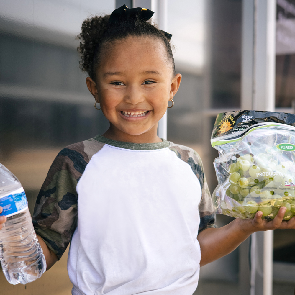 Photo of girl holding a bottle of water and bag of green grapes