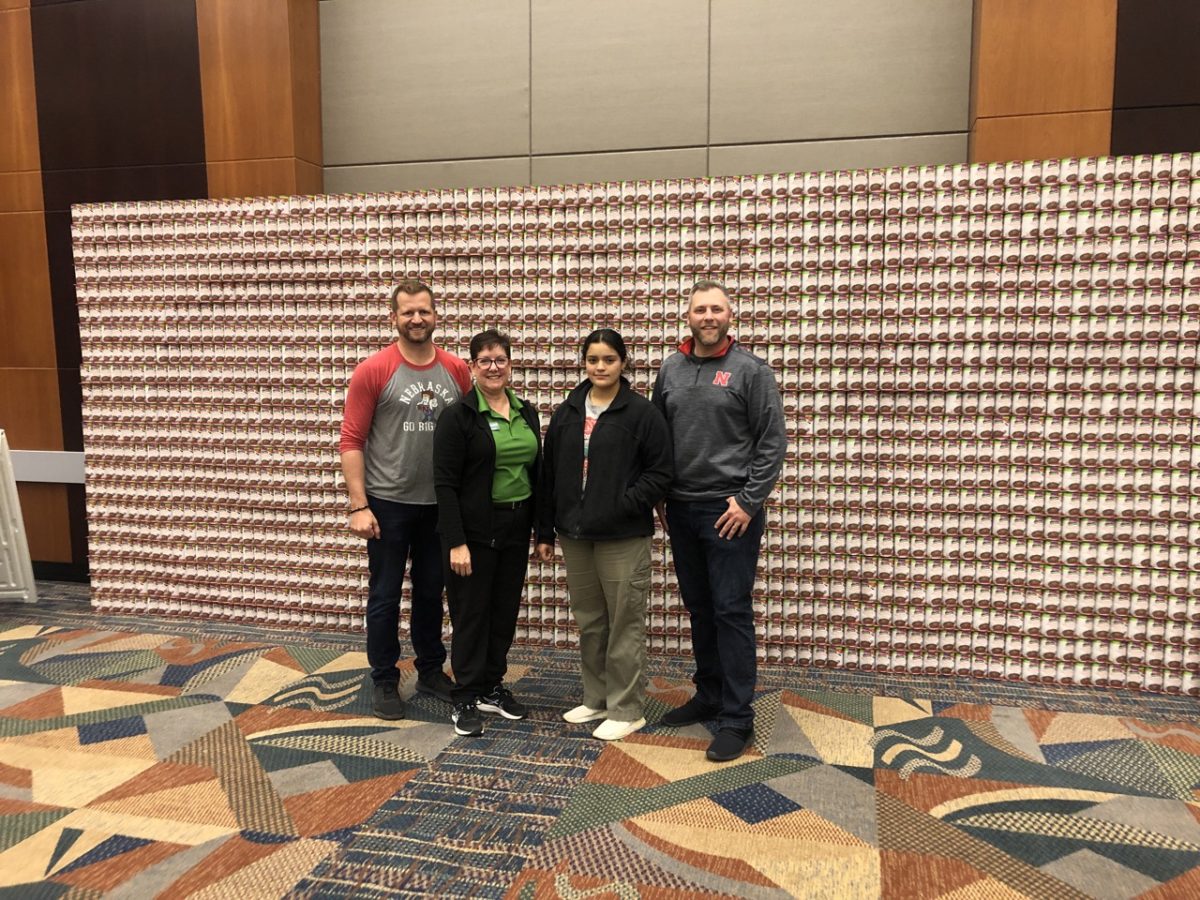 Photo of Kelly Ptacek, VP of External Affairs, and HDR team members in front of "Wave of Impact" built from canned food