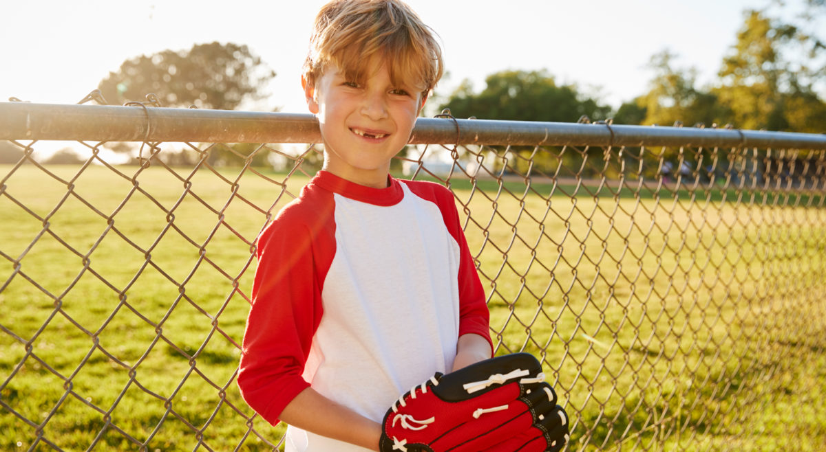 Photo of a child standing outside with a baseball glove