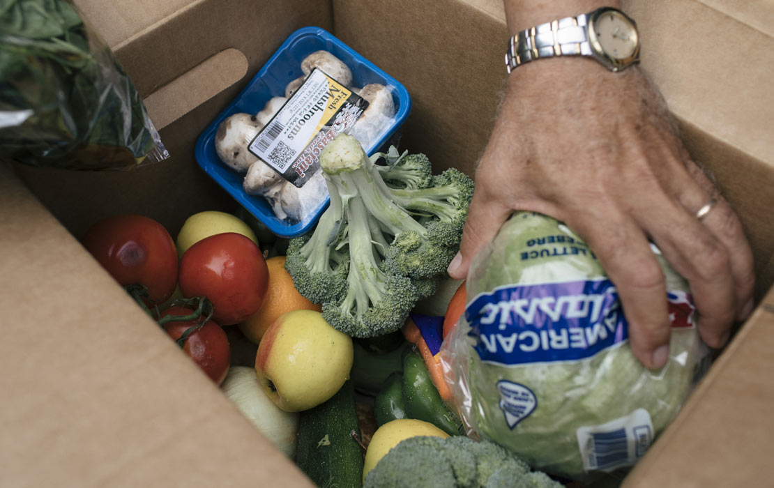 Photo of person grabbing fresh produce out of a box